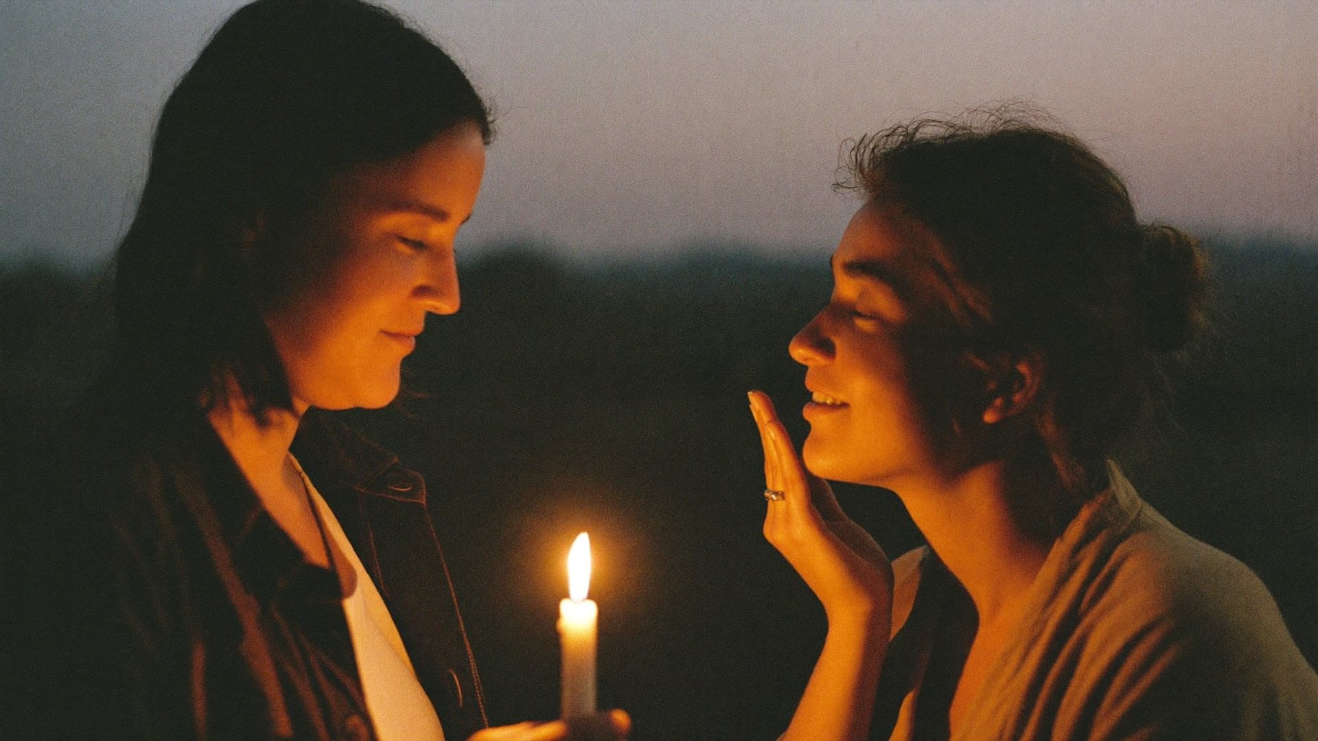 Two people in candlelight, one gently holding the other's face
